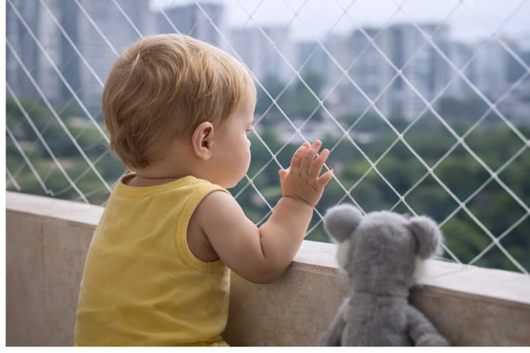 Niño seguro mirando por balcón con malla de seguridad